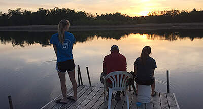 Teens fishing on dock at sunset